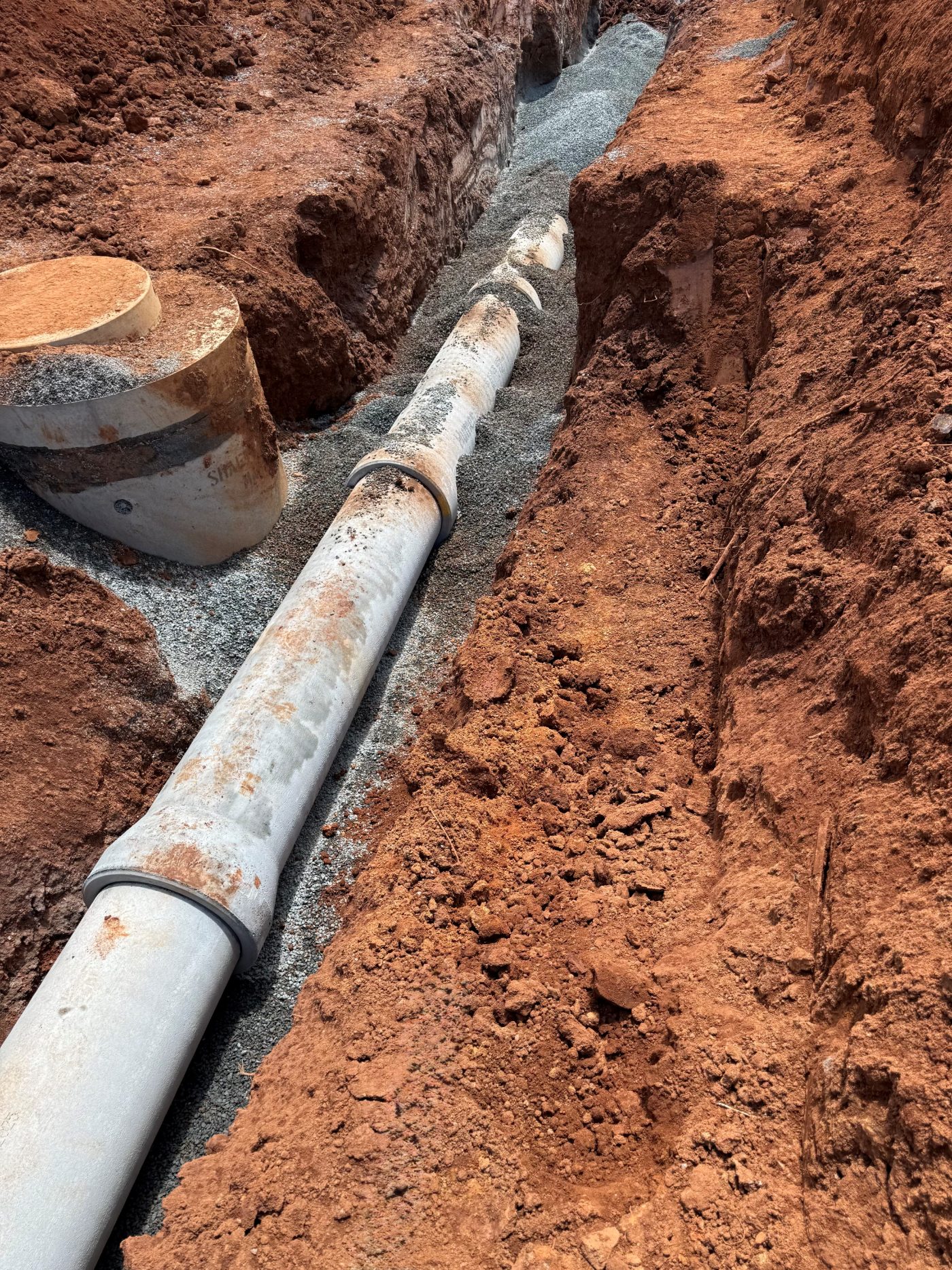 Concrete sewer main and manhole base laid in an open trench