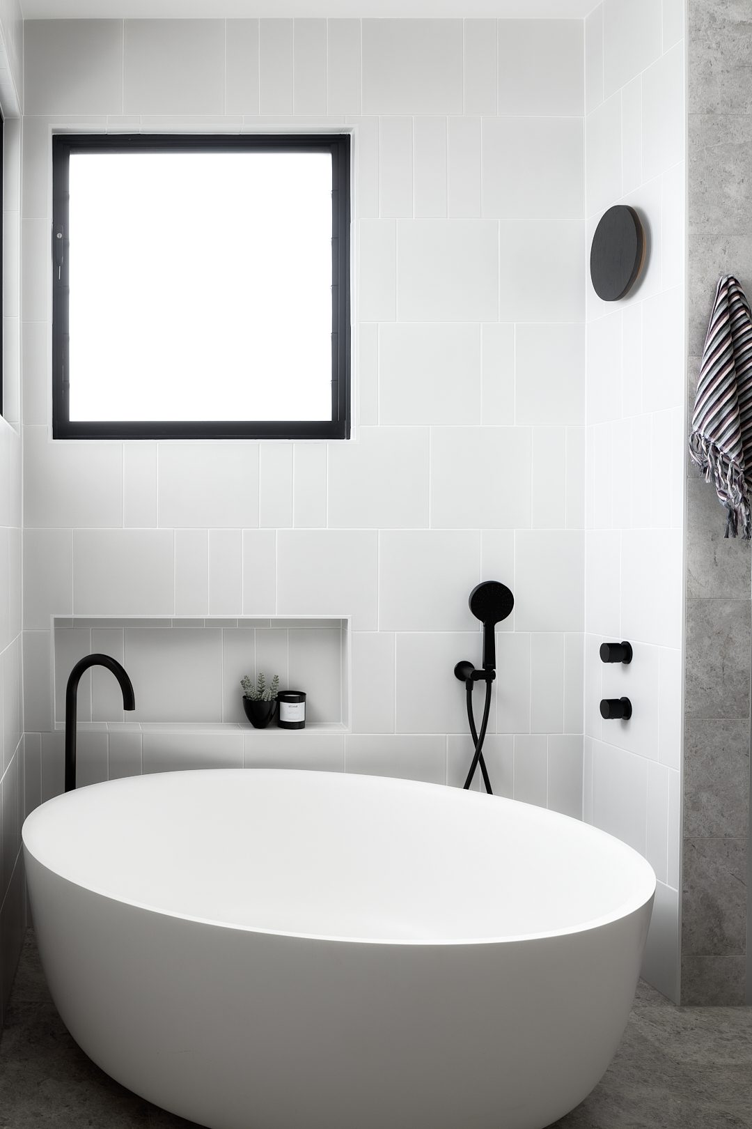 Freestanding bath with black floor-mounted mixer and recessed niche