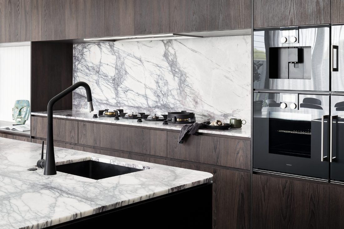 Kitchen with marble benchtops, black gooseneck mixer and undermount sink