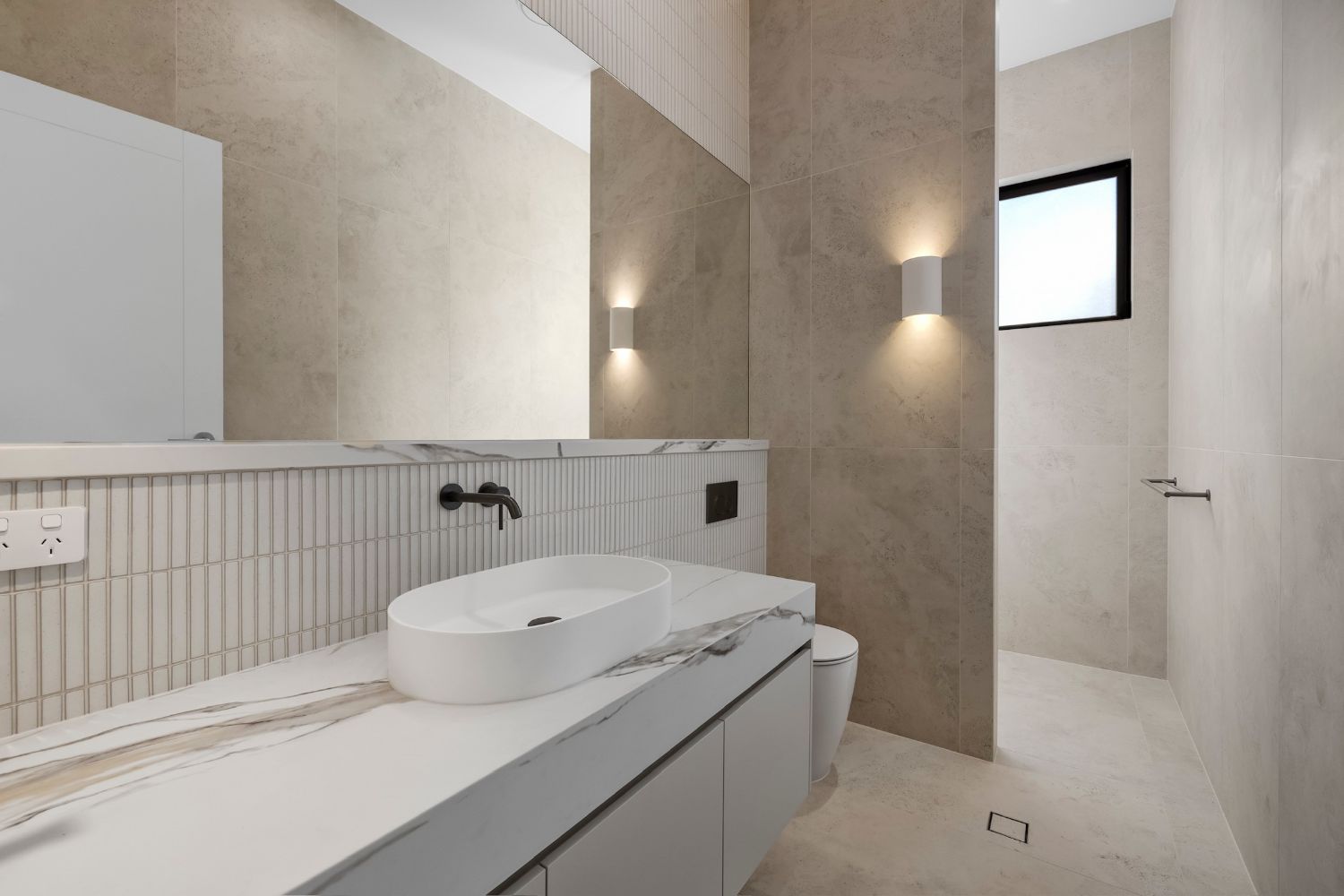 Powder room with oval basin, marble benchtop and matt black tapware