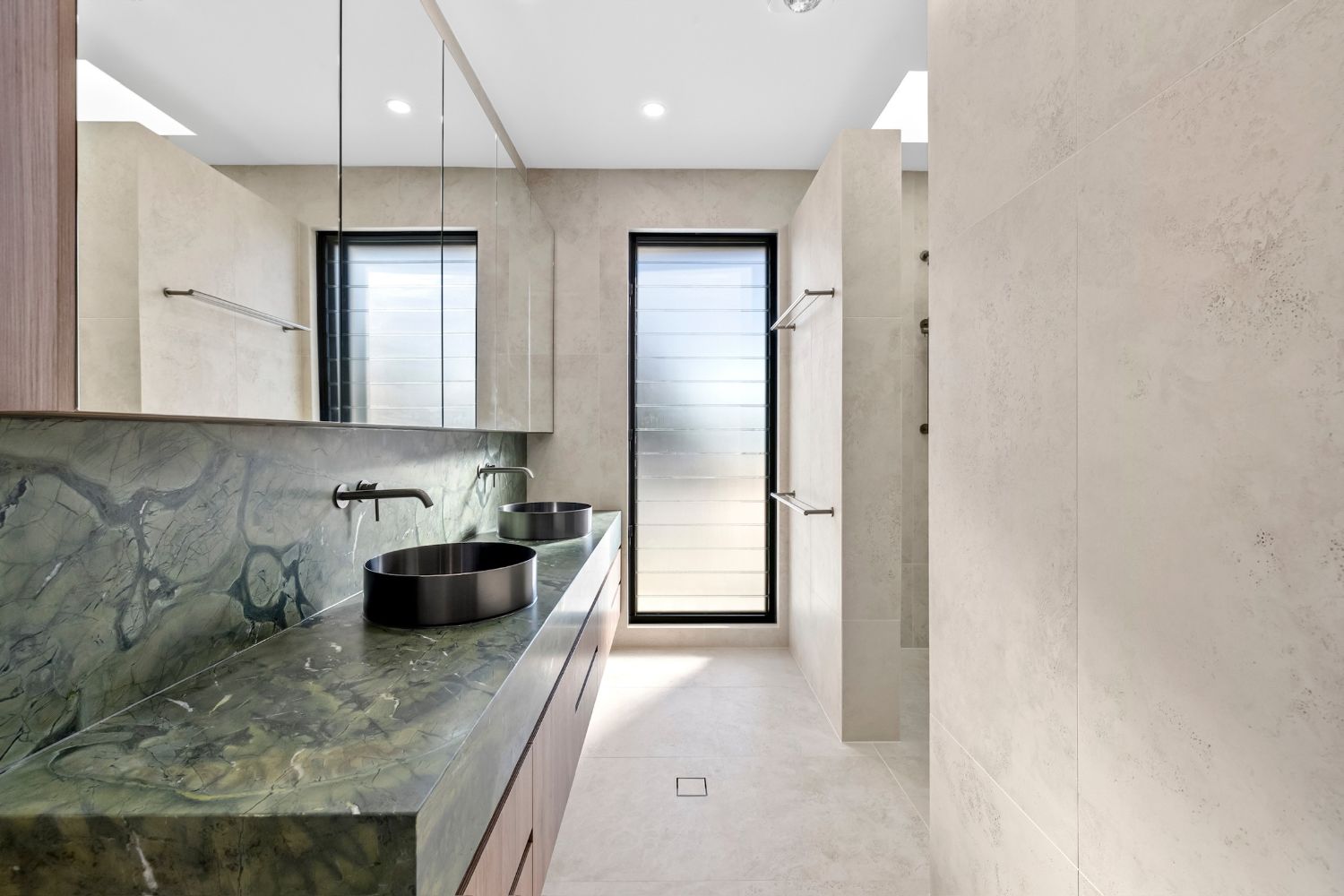 Twin basins on a green stone vanity with wall-mounted tapware